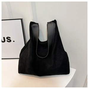 Detailed close-up of a large black suede tote bag with durable leather handles and wide opening