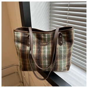 Detail of checkered tote bag with wool texture, brown leather trim and metal logo
