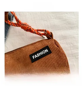 Detail of brown corduroy bag with FASHION patch and colorful braided shoulder strap