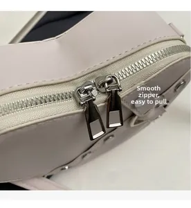 Close-up of smooth silver dual zippers on the premium beige leather shoulder bag