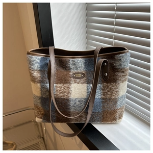 Close-up of blue and brown checkered tote bag with plush texture and leather straps