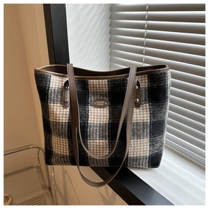 Detailed close-up of a plaid tote bag featuring checkered tweed and brown leather straps
