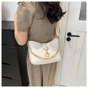Close-up of a white leather bucket bag featuring a gold chain and metal buckle closure
