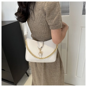 Close-up of white leather bucket bag with chunky gold chain and wide woven shoulder strap