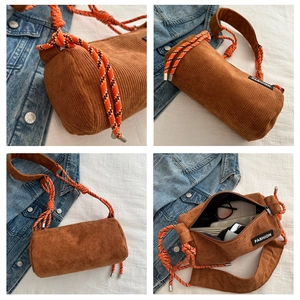 Detail view of brown corduroy cylinder bag with colorful braided rope shoulder strap