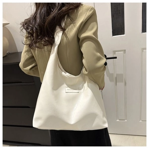 Minimalist beige PU leather tote bag worn as a shoulder bag on a khaki blazer