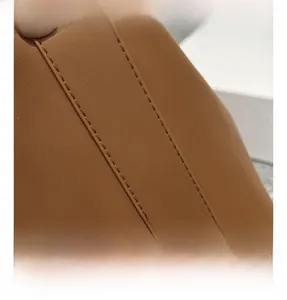 Macro view of brown leather texture and double stitching on minimalist shoulder bag