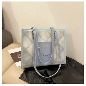 Détail du sac cabas matelassé bleu clair avec chaîne en métal doré et lettrage fashion
