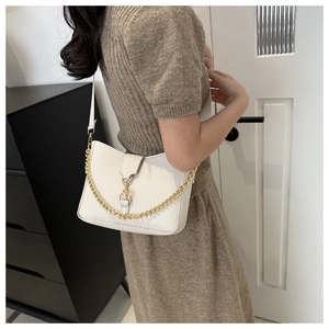 Detailed side view of a white minimalist bucket bag with golden chain and leather strap