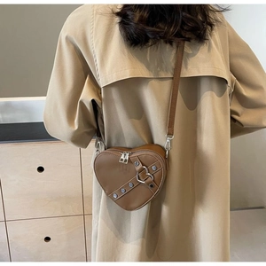 Detailed back view of a brown heart-shaped leather crossbody bag worn on a beige coat