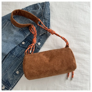 Detailed shot of brown corduroy cylinder bag with vibrant orange woven rope strap