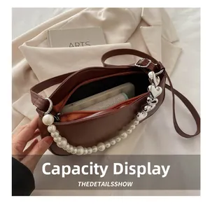Brown shoulder bag with pearl and heart chain detail showing interior phone capacity