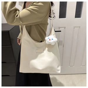 Detail of cream white faux leather tote bag with star plush charm and brand patch