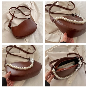 Detail of brown leather wave-shaped bag with pearl handle, heart charm and inner capacity