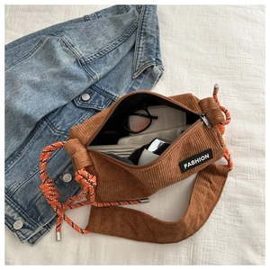 Detail view of brown corduroy crossbody bag showing interior space and orange rope strap
