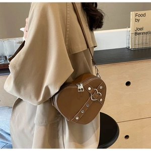 Detail of vintage brown heart-shaped bag with silver buckles and rivets on strap