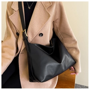 Detail of black leather tote bag with gold buckle and adjustable shoulder strap