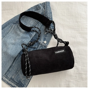 Detail view of black corduroy barrel bag with woven rope strap and FASHION label
