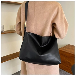 Detail view of adjustable leather strap and gold buckle on a black hobo shoulder bag