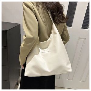Close-up of cream-colored large tote bag with Fashion & Bags embossed leather patch