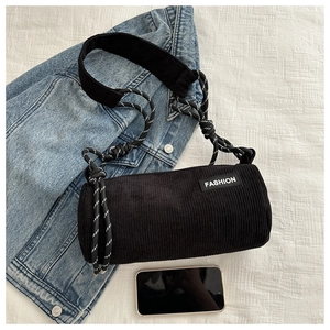 Close-up of black corduroy cylinder bag with FASHION label and woven rope details