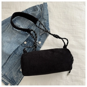 Detail of black corduroy cylinder crossbody bag with woven rope strap and texture