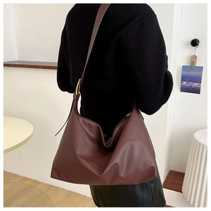 Close-up of high-capacity burgundy leather tote bag showing drape texture and shoulder strap