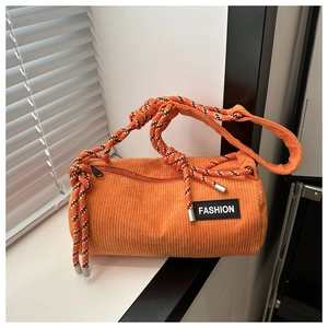 Detail of orange corduroy barrel bag with thick woven rope strap and fashion label