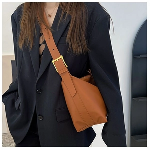 Detail of orange tote bag with wide strap and large golden square buckle on blue blazer