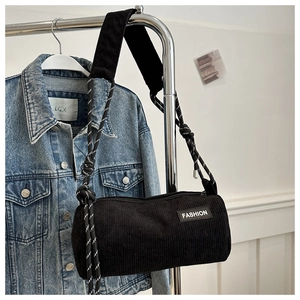 Detail of black corduroy barrel crossbody bag with FASHION label and rope strap