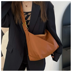 Detail of a large brown tote bag showing its soft leather texture and adjustable strap