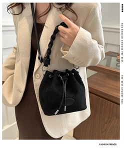 Détail du sac seau en daim noir avec poignée tressée et cordon sur un mannequin