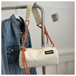 Detail of cream corduroy cylinder bag with textured fabric and vibrant rope strap