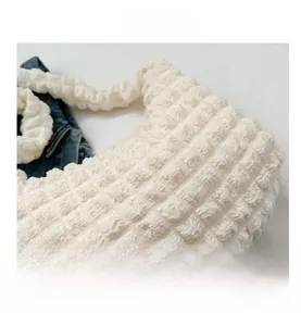 Close-up of white popcorn fabric texture on a stylish underarm bag with 3D bubble effect