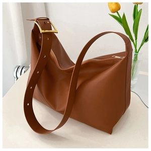 Detail of a large brown matte leather tote with a wide studded strap and gold buckle