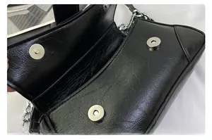 Detail view of black crinkled leather bag showing silver magnetic buckles and chain