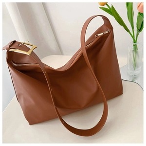 Detailed close-up of brown faux leather shoulder bag with gold hardware on white surface