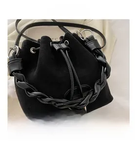 Détail du sac seau noir en daim mat avec anse en cuir tressé et anneaux métalliques