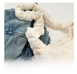 Detail of off-white bubble texture fabric and ruched shoulder strap on tote bag