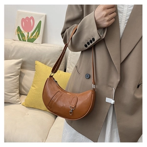 Detail of a brown glossy crescent shoulder bag with metallic buckle and adjustable strap