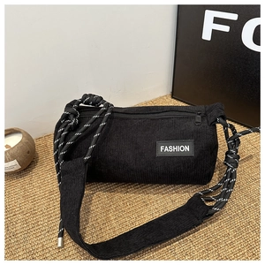 Detail of black corduroy cylinder crossbody bag with fashion patch and rope strap