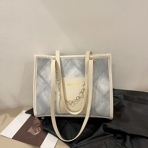 Sac fourre-tout en denim bleu avec bordure crème et chaîne dorée sur cuir noir