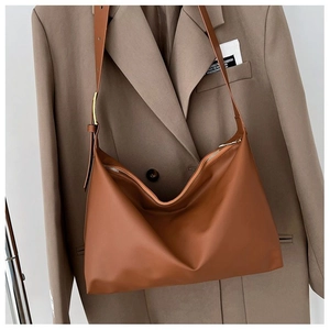 Close-up of brown minimalist tote bag with smooth gold zipper and leather strap texture