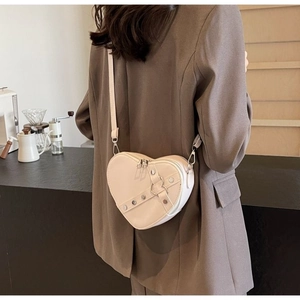 Detail of cream heart-shaped crossbody bag with silver studs and adjustable strap