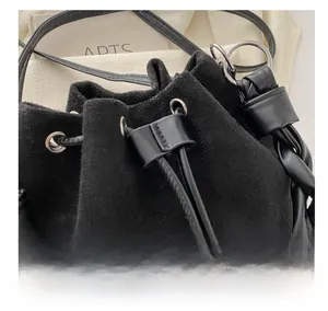 Détail du sac seau en suède noir avec cordon de serrage et bandoulière tressée