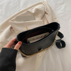 Fashionable black bucket bag with gold chain and wide strap shown from a 45-degree angle