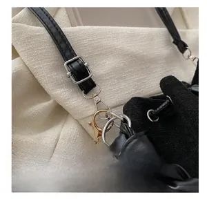 Détail macro d'une bandoulière en cuir noir réglable avec boucles argentées et métal mixte