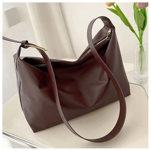 Detail of dark brown tote bag showing smooth matte leather texture and adjustable strap