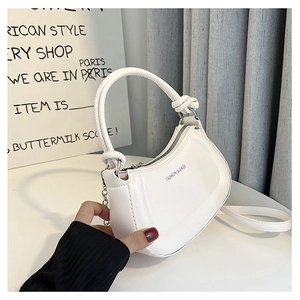 Detail of white crescent bag featuring a unique knotted handle and zipper closure