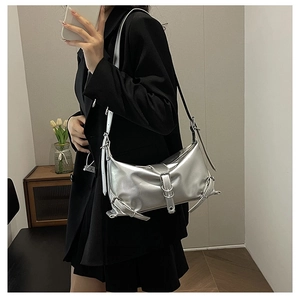 Chic metallic silver underarm bag with adjustable buckles worn as a crossbody shoulder bag